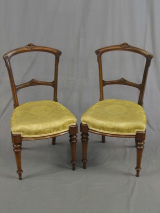 A pair of Victorian carved walnut rail back dining chairs with carved mid rails and upholstered seats, raised on turned supports