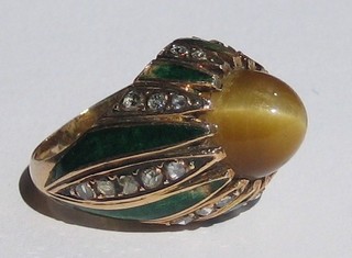 An Eastern gold dress ring set a cabouchon cut tiger's eye, the shank set numerous diamonds and enamelled panels