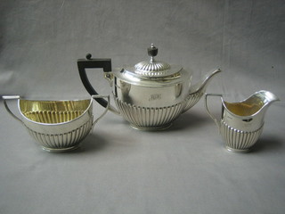 An Edwardian silver 3 piece tea service of oval form with demi-reeded decoration, comprising teapot, twin handled sugar bowl and cream jug, Sheffield 1909 31 ozs, inscribed and engraved