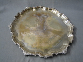 A circular silver plated salver with bracketed border, raised on 3 scrolled feet 12"