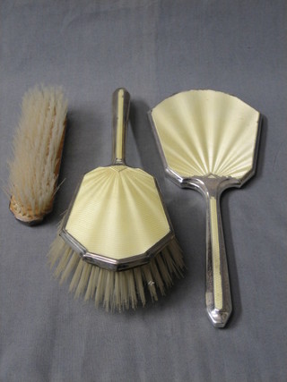 An Art Deco 3 piece silver and yellow enamel back dressing table set comprising hand mirror, hair brush and clothes brush, Birmingham 1939 (some damage to the enamel)