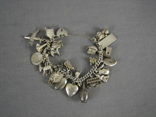 A lady's silver curb link charm bracelet hung 26 various charms complete with padlock clasp