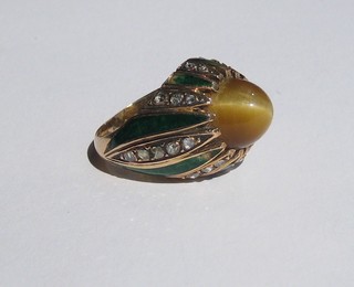 An Eastern gold dress ring set a cabouchon cut tiger's eye, the shank set numerous diamonds and enamelled panels