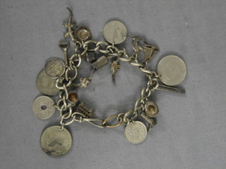 A silver curb link charm bracelet hung various coins and charms