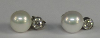 A pair of lady's large pearl drop earrings surmounted by diamonds (1 pearl with corrosion)