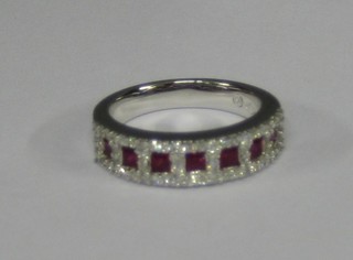 A lady's 18ct gold dress ring set 7 square cut rubies supported by diamonds (approx 0.55/0.65ct)