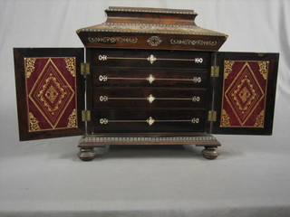 A handsome Victorian rosewood and inlaid mother of pearl sewing box of sarcophagus form, the hinged lid revealing a well fitted interior and 5 carved mother of pearl bobbins, the front enclosed by panelled doors revealing 2 drawers and writing slope fitted 2 glass inkwells, having circular drop handles to the sides, raised on bun supports 13" (1 support missing and requires some attention)