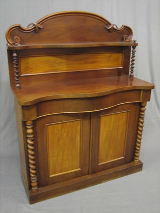 A Victorian mahogany chiffonier of serpentine outline and with raised back, the base fitted a drawer above a double cupboard flanked by a pair of spiral turned columns 42"