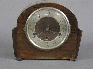 A 1930's 8 day chiming mantel clock with silvered dial and Arabic numerals contained in a walnut arch shaped case