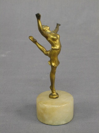 An Art Deco gilt painted spelter figure of a standing dancing girl with arms outstretched, raised on a white marble socle base, 6"