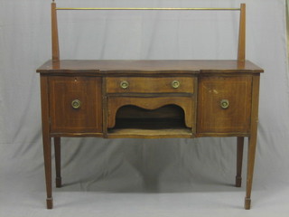 An Edwardian inlaid mahogany Georgian style sideboard of serpentine outline and with brass rail back, the base fitted 1 long drawer above a recess flanked by a pair of cupboards, raised on square tapering supports ending in spade feet 54"