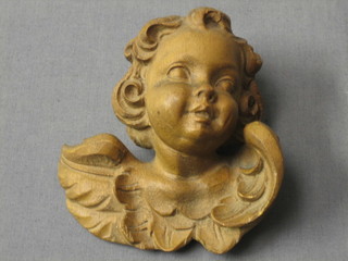 A carved lime wood figure in the form of the head and shoulders of a cherub 4"