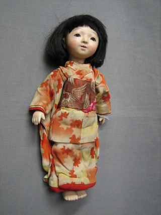 An Oriental porcelain doll with open eyes and articulated limbs
