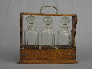 An oak 3 bottle tantalus fitted 3 cut glass spirit decanters