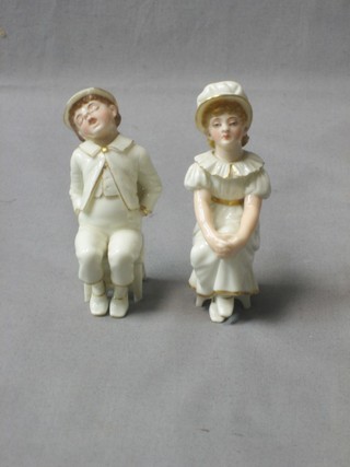 A 19th Century porcelain figure of a seated bonnetted girl, 4" together with a seated dozing boy (chip to hat)