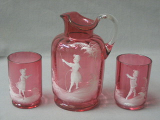 A Mary Gregory cranberry glass jug with clear glass handle decorated a figure of a standing girl with stick and hoop 6 1/2" together with 2 matching goblets 3 1/2" (gilding rubbed and slight chip to 1)
