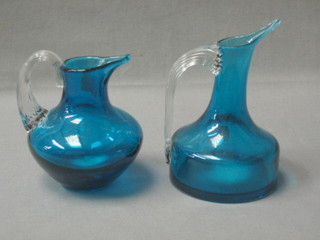 A Whitefriars blue glass jug with clear glass handle, raised on a square foot 6" and a similar jug 4"