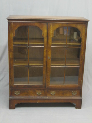A 1950's Queen Anne style walnut bookcase, the interior fitted adjustable shelves enclose by astragal glazed panelled doors, the base fitted 2 drawers, raised on bracket feet 36"