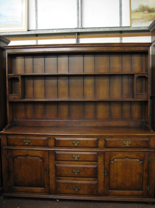 A 20th Century oak dresser with moulded cornice the raised back fitted shelves and 3 long drawers, the base fitted 3 short drawers flanked by double cupboards, raised on bracket feet 71" 
