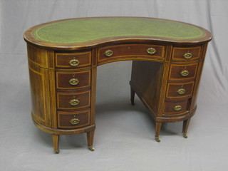 An Edwardian inlaid and crossbanded mahogany kidney shaped desk with inset tooled leather writing surface, above 1 long and 8 short drawers, raised on square tapering supports ending in brass caps and castors 47"