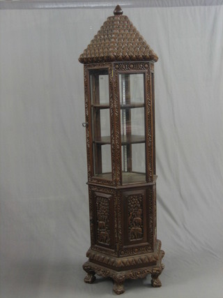 A 20th Century carved Eastern hexagonal pagoda display cabinet, the upper section enclosed by panelled doors, the base enclosed by panelled doors, raised on scroll feet 77"