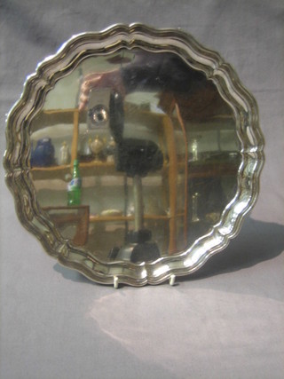 A circular silver plated salver with bracketed border, raised on claw and ball feet 10"