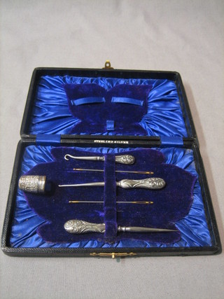 An Edwardian silver 4 piece needlework set comprising thimble, silver button hook, 2 silver handled sewing implements contained in a leather fitted case, Chester 1906