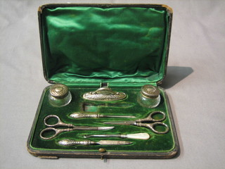 An Edwardian 8 piece silver backed manicure set comprising buffer, 2 circular jars with lids, 2 pairs of scissors and  3 manicure implements, Birmingham 1904 (brush missing), cased