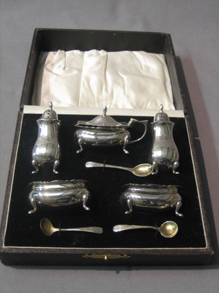 A silver 5 piece condiment set comprising oval mustard pot with blue glass liner, pair of salts with blue glass liners, pair of peppers and 3 condiment spoons, Birmingham 1926, cased