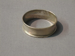 An oval silver napkin ring with engine turned decoration