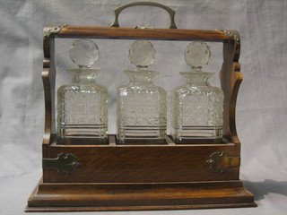 An oak and silver plated tantalus with 3 cut glass decanters (some damage to the decanters and no key)
