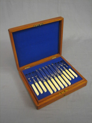 A set of 12 Victorian silver plated fruit knives and forks with ivory handles contained in a walnut case