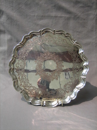 A circular engraved silver plated salver raised on 4 scrolled supports 16"