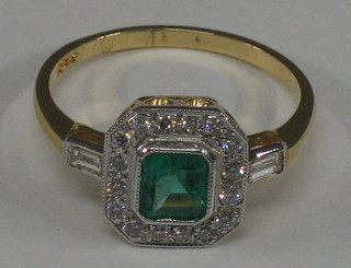 A lady's 18ct yellow gold dress ring set a square cut emerald supported by diamonds and having baguette cut diamonds to the shoulders