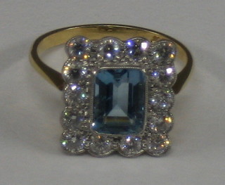 A lady's attractive 18ct gold dress ring set a square cut aquamarine supported by 14 diamonds (approx 0.90ct)