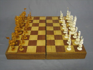 An Eastern brown and white ivory chess set, each piece with a puzzle ball to the base, together with a folding board