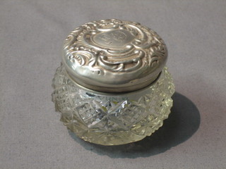 A circular cut glass dressing table jar with embossed silver lid