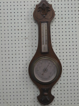 A 1930's aneroid barometer and thermometer contained in a carved oak wheel case