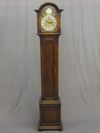 A chiming Granddaughter clock, the 7 1/2" arch shaped brass dial with silvered chapter ring contained in an oak Jacobean style case with sliding hood 67"