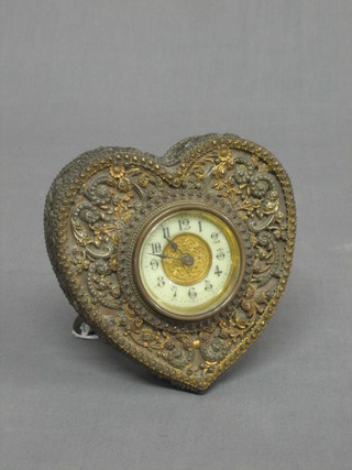 A 19th/20th Century bedroom clock with 2" circular porcelain dial with Arabic numerals contained in a heart shaped embossed metal case