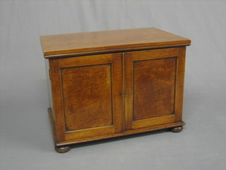 A 19th Century mahogany table top cabinet, the interior fitted a shelf enclosed by panelled doors, raised on bun feet 18"