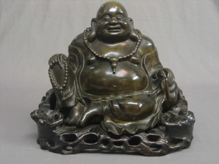 A 19th/20th Century bronze figure of a seated Buddha raised on a hardwood stand 15"