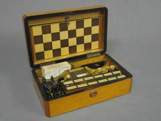 A Victorian games compendium containing a chess set, set of dominoes, drafts, playing cards and cribbage board, all contained within a satinwood lozenge shaped box 11"