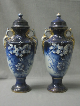 A pair of Edwardian pottery blue glazed and floral patterned twin handled urns and covers 13"
