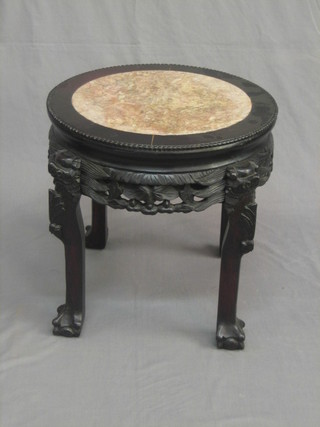 A circular Eastern hardwood jardiniere stand with pink marble top, raised on carved supports 18"