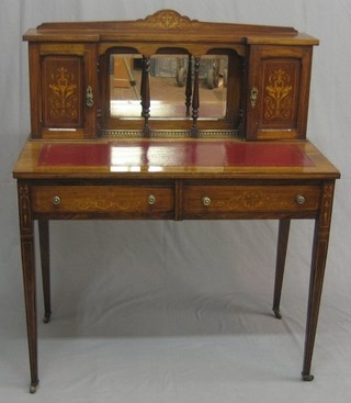 A Victorian rosewood writing table with raised mirrored back flanked by a pair of cupboards fitted pigeon holes and enclosed by panelled doors, the base with inset tooled leather writing surface above 2 long drawers, raised on square tapering supports 36"