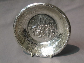 A circular Dutch silver plated bowl decorated figures feasting, raised on 3 bun feet 7"