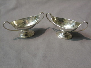 A handsome pair of Victorian oval twin handled salts, raised on spreading feet with armorial decoration, London 1883, 3 ozs