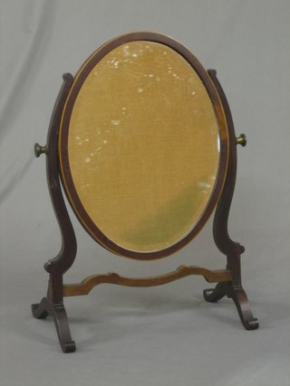 A 19th Century oval bevelled plate dressing table mirror contained in an inlaid mahogany swing frame