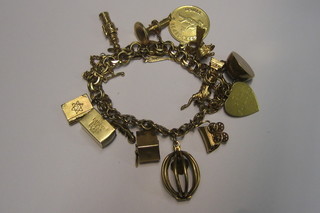An American 14ct gold multiple link charm bracelet hung 14 various charms - Jewish Holy book, dollar bill, telephone, one armed bandit, caged heart, covered wagon, Statue of Liberty, kettle, heart pendant, dove, circular Zodiac pendant, chamber stick, knife fork and spoon and a Jewish pendant 2 ozs